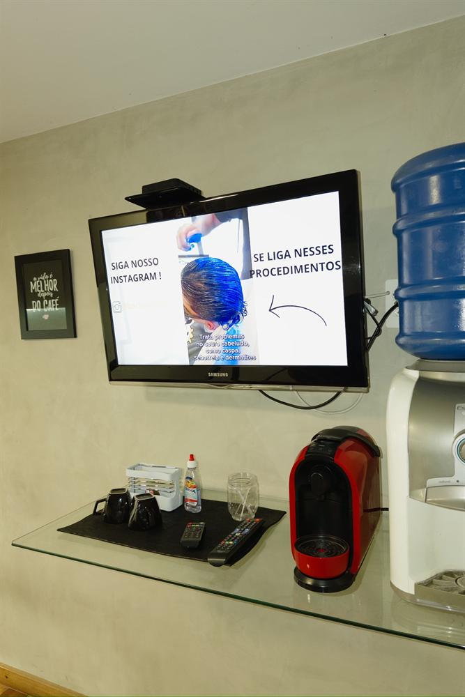 Estação de café e TV com conteúdo da barbearia