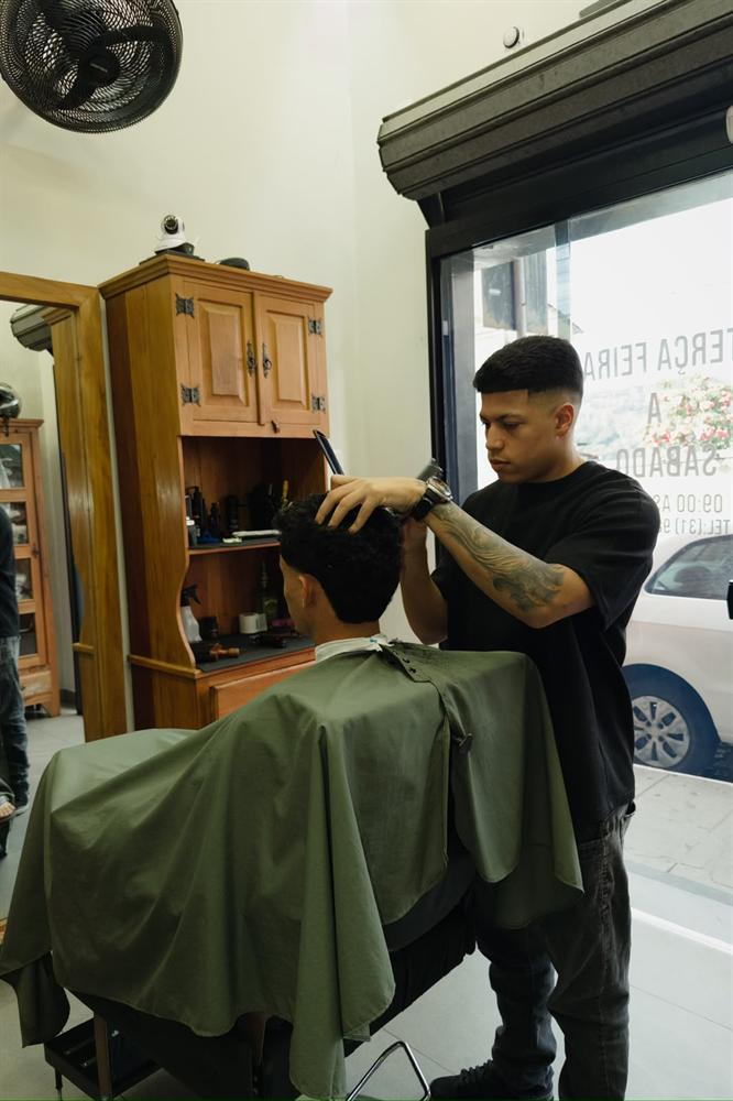 Atendimento na cadeira junto à vitrine da barbearia