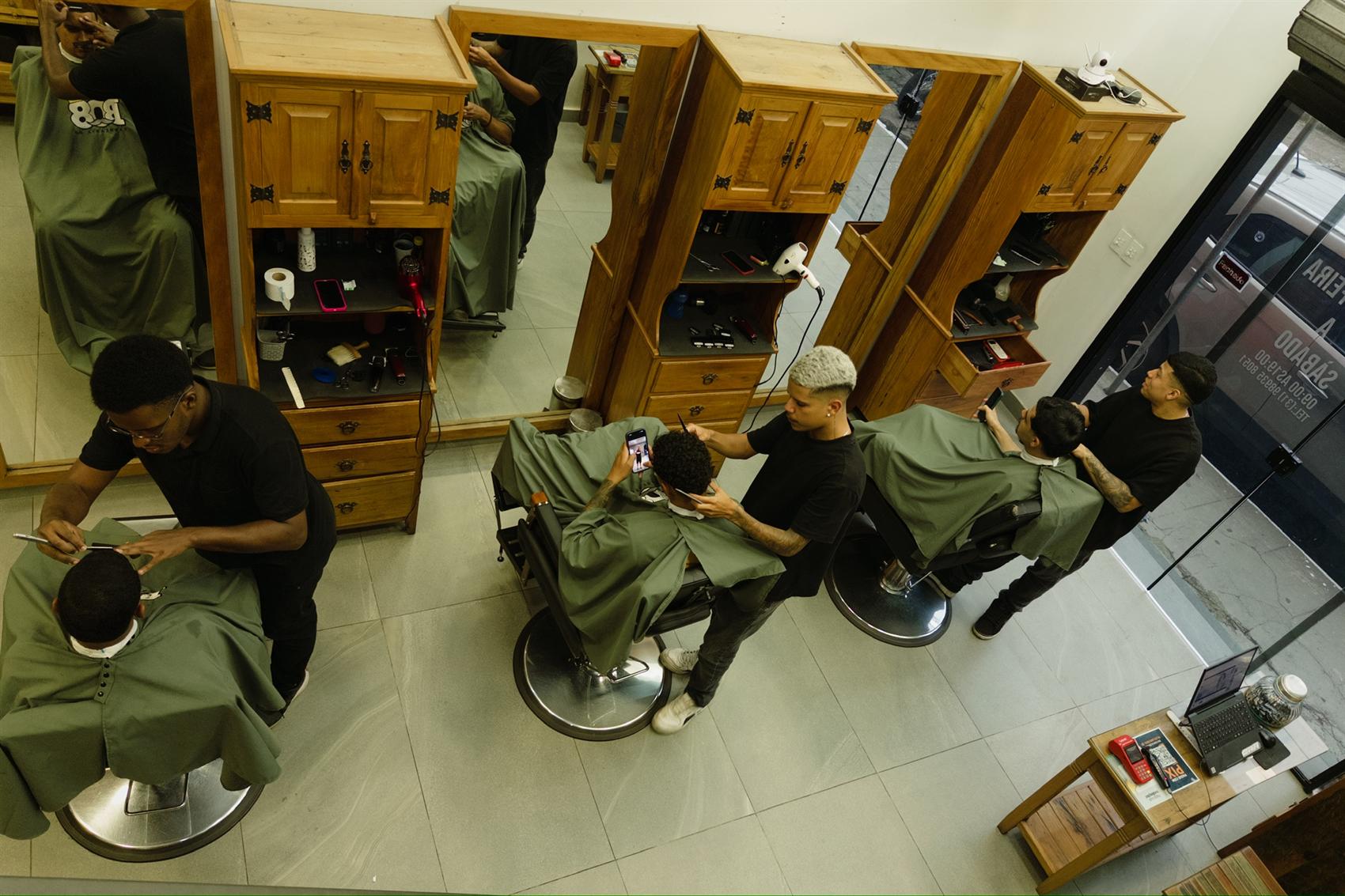 Vista de cima da Barbearia 08 com três barbeiros atendendo ao mesmo tempo